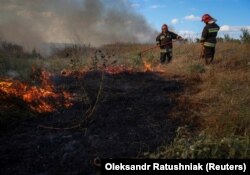 Украинские пожарные тушат пожар недалеко от линии фронта в Запорожской области. Украина, 3 сентября 2023 года