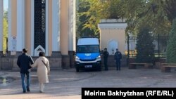 Полицейские и микроавтобус с проблесковыми маячками у входа в Центральный парк в Алматы. 25 октября 2023 года