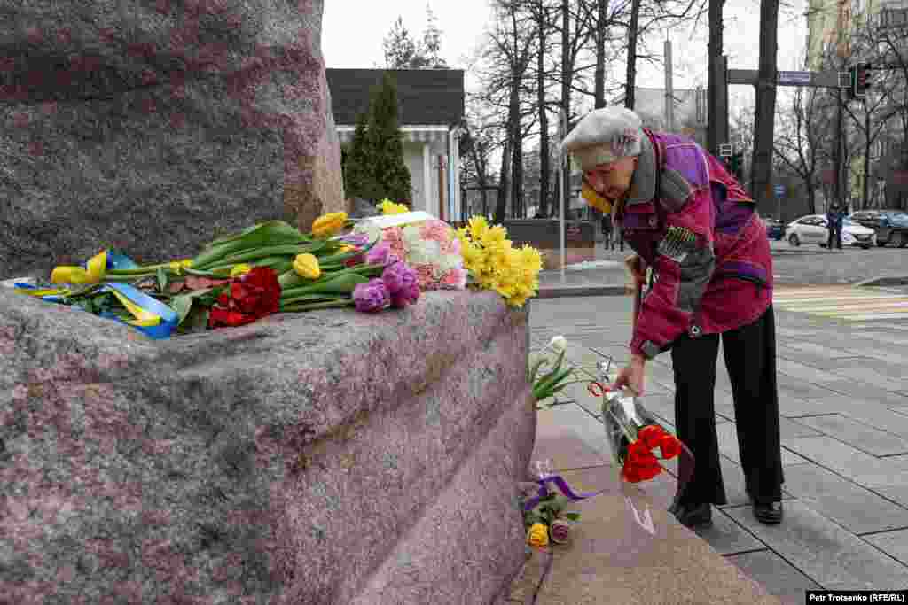 Женщина возлагает букет к памятнику