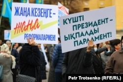 Участники митинга в поддержку президента Касым-Жомарта Токаева закрывают лица транспарантами. Алматы, 19 марта 2022 года