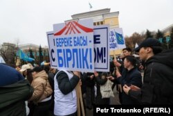 Активист в белой жилетке собирает транспаранты у участников митинга в поддержку президента Касым-Жомарта Токаева. Алматы, 19 марта 2022 года