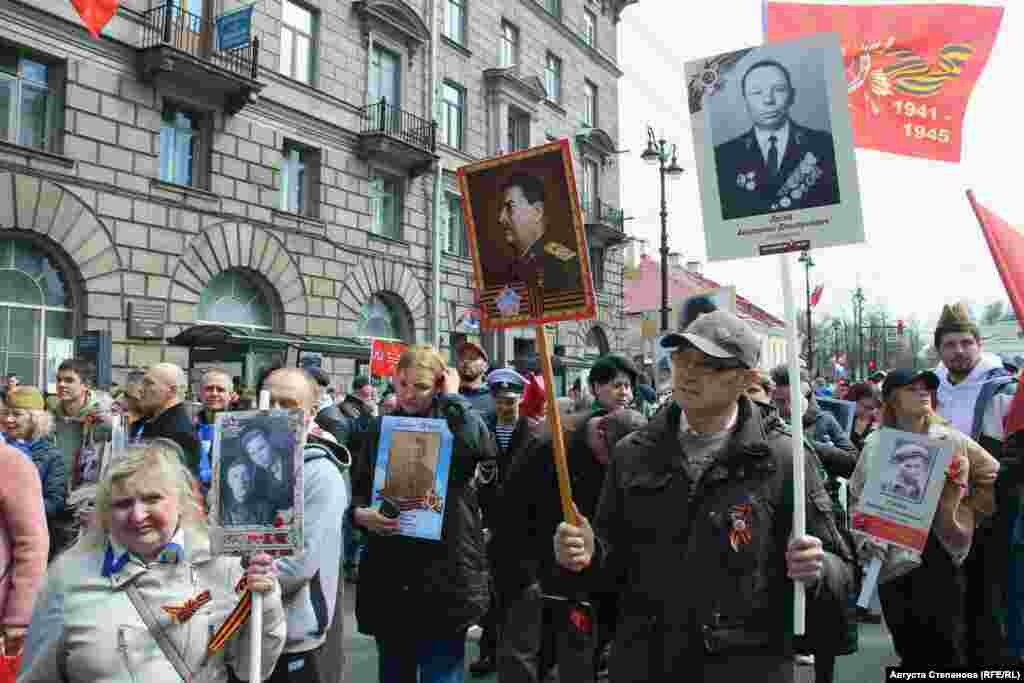 Участник акции &quot;Бессмертный полк&quot; в Петербурге с изображением своего родственника в одной руке и фотографией Иосифа Сталина в другой&nbsp;