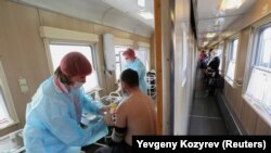 Пациент получает дозу вакцины "Спутник V в вагоне медицинского поезда на железнодорожной станции в городе Тулун Иркутской области