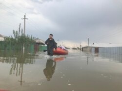 Спасатели помогают жителям села Оргебас добраться к домам на лодке, чтобы забрать документы.