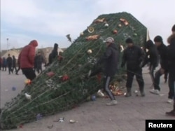 Молодые люди стоят у разваленной новогодней елки. Жанаозен, 16 декабря 2011 года.