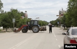 Полицейский блокирует улицу на месте спецоперации против подозреваемых боевиков. Актобе, 10 июня 2016 года.