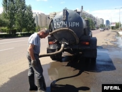 Рабочий закачивает ливневую воду в автоцистерну на Левом берегу Астаны. 2 августа 2013 года.