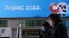 China -- People walk past a banner with a sign of Beijing 2022 Winter Olympic Games, 100 days ahead of the opening of the event, in Beijing, China October 27, 2021. REUTERS/Tingshu Wang