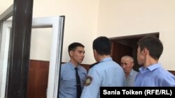 Полицейские заводят Абловаса Джумаева в зал суда. Актау, 12 сентября 2018 года.