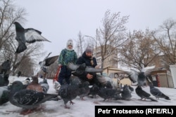 Женщина с ребенком кормят голубей на центральной улице Петропавловска. Северо-Казахстанская область, 19 декабря 2020 года.