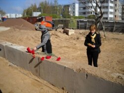 2011 год, внучки погибших в лагере солдат возлагают цветы на месте строительства