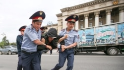 Полицейские несут задержанного на акции протеста в автозак. Алматы, 10 июня 2019 года.