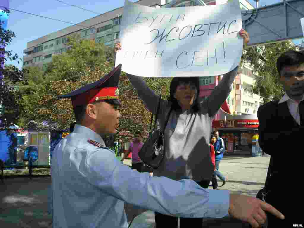 Полиция останавливает акцию поддержки Жовтиса. - Сторонница Жовтиса Ольга Уразбекова держит плакат с надписью «Сегодня Жовтис, завтра - Вы». Рядом стоит полицейский, который приказывает остановить акцию. Алматинский Арбат, 30 сентября 2009 года.