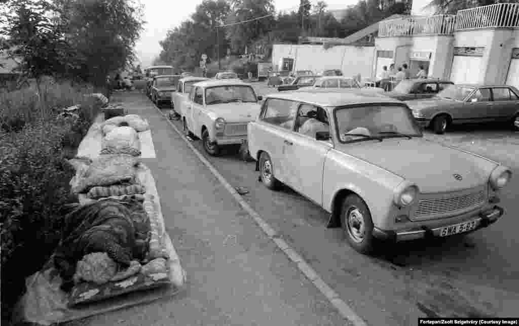 Беженцы из Восточной Германии спят рядом со своими автомобилями Trabant в Будапеште. После бархатной революции в Венгрии в 1989 году тысячи немцев из Восточной Германии, которые жили в условиях неусыпным контролем со стороны тайной полиции Штази, устремились на восток. Венгрия была одним из &laquo;братских социалистических государств&raquo;, куда им разрешалось ездить